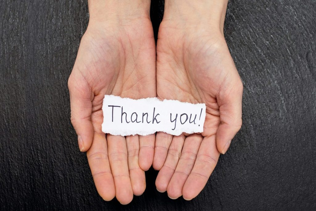 hands with a thank you note